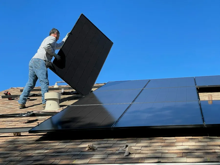 Vakman installeert zonnepanelen op een dak